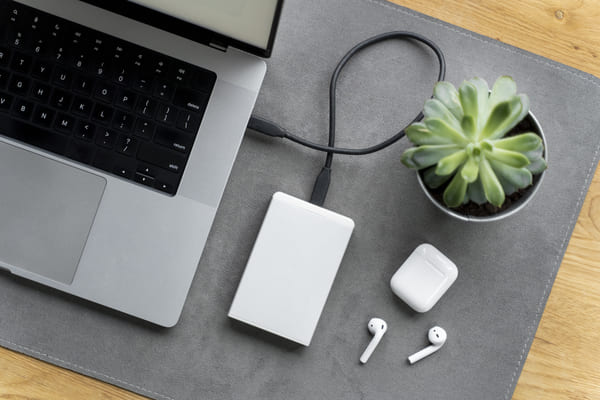 laptop, disco duro externo y auriculares inalambricos con carcasa de plástico sobre una mesa